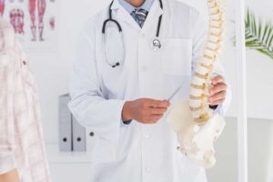 Chiropractic safety discussion with a patient reviewing symptoms beside an examination table.